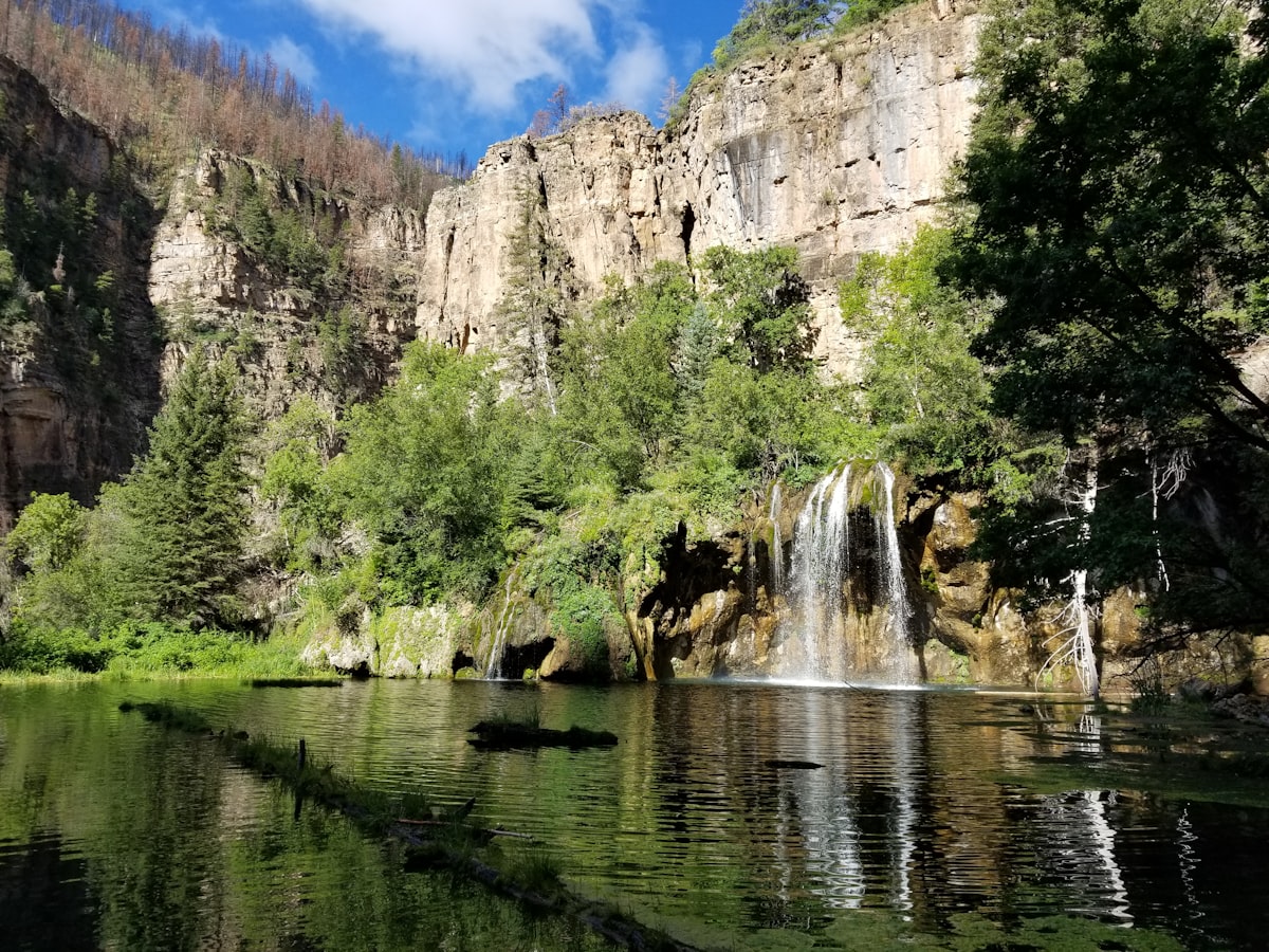 Turquoise waterfall cascading into a hanging lake in a canyon